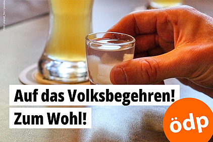 Eine Hand hält ein volles Schnapsglas und lädt zum Anstoßen ein